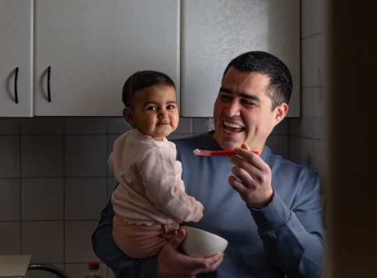 Hombre dando de comer bebé, ningún hogar sin alimento